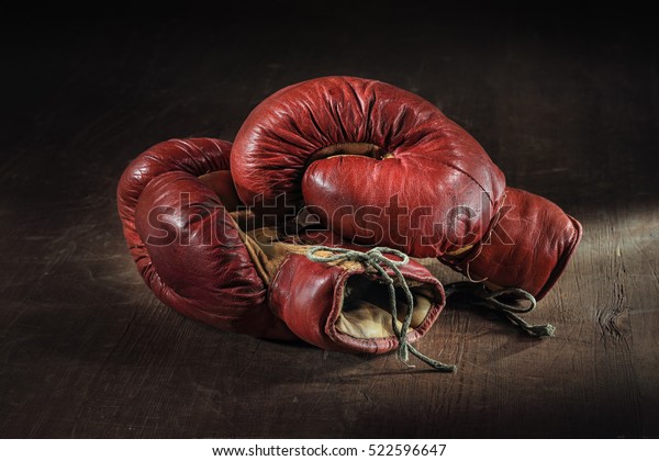 Old red boxing\
gloves on wooden\
background.