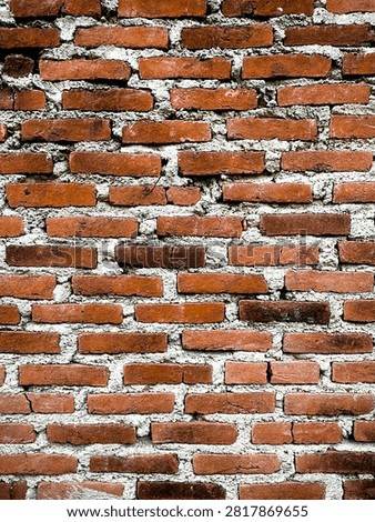 Old red brick wall with rough cement mortar, showcasing weathered textures and rustic masonry. Ideal as a construction, architecture, or background pattern