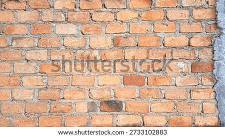Old red brick wall texture with visible cement mortar in natural daylight. Rustic brick pattern background showing rough surface details, weathered tones, and traditional construction style. Ideal for architectural design, urban background, industrial themes, renovation concepts, and textured wallpaper use.