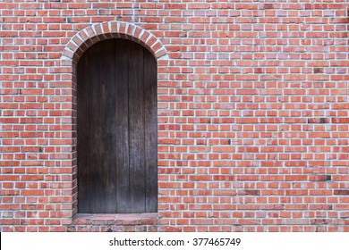 Old red brick wall with wooden door.
