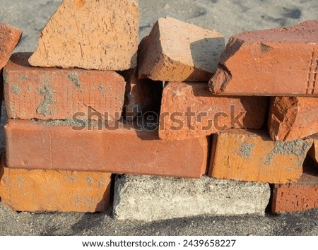 Old red bricks stacked on the sand. Broken bricks. Building materials unsuitable for use