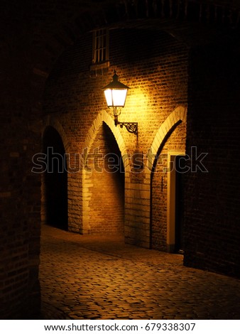 Old red bricks wall and light hanging on the wall. Night. Arch. fortress. Holland