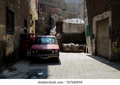 An old  red car parked in an empty alley  