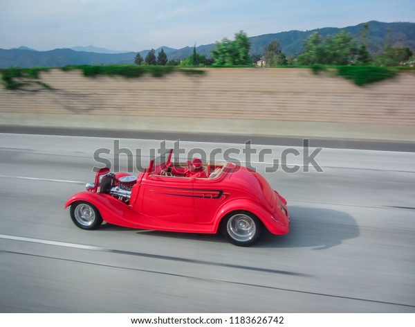 An old red car rides on the Los Angeles road. USA.\
Spring 2015