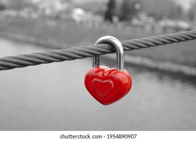 Old red heart shaped lock on wire rope. Love lock on the bridge.