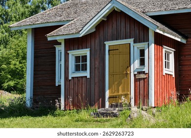 Old red logcabin in Finland. Red cabin next to forest and meadow in summer.