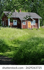 Old red logcabin in Finland. Red cabin next to forest and meadow in summer.