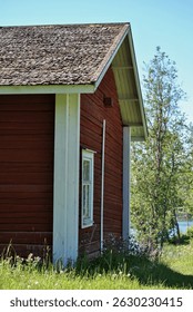 Old red logcabin in Finland. Red cabin next to forest and meadow in summer.