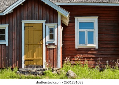 Old red logcabin in Finland. Red cabin next to forest and meadow in summer.