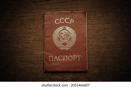 An old red passport of the Soviet Union with the coat of arms on the cover. Wooden background in retro style. The symbol of the USSR.