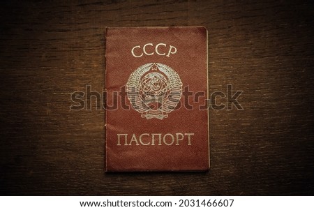 An old red passport of the Soviet Union with the coat of arms on the cover. Wooden background in retro style. The symbol of the USSR.