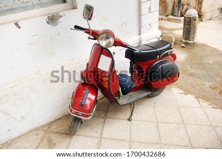 An old red retro scooter is parked on a Zanzibar street.