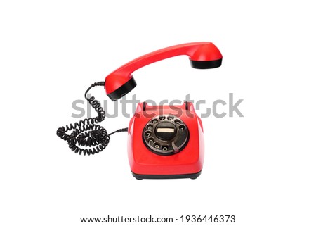 Old, red rotary dial telephone with hanging in the air receiver, isolated on white