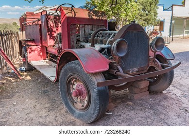 Old red rusty fire engine up on blocks in western town