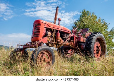 Old Red Rusty Tractor In A Field