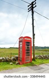 Old red telephone booth with a pole at the coast of the scottish island Mull, copy space