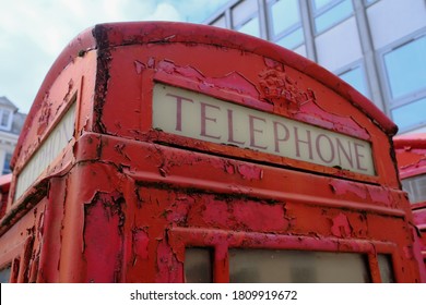 Old Red Telephone Booth With Rust And Stripped Paint. Concept For Out Of Dated Technology And Equipment. Iconic British Red Telephone Booth.