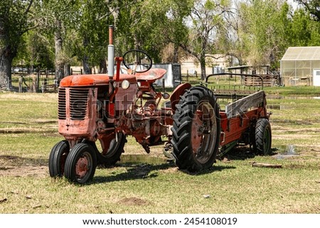 An old red tractor with a farm implement in a field.