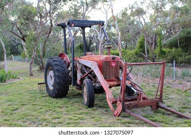 Old Red Tractor With Forks And Stick Rake Behind In Paddock, Australia