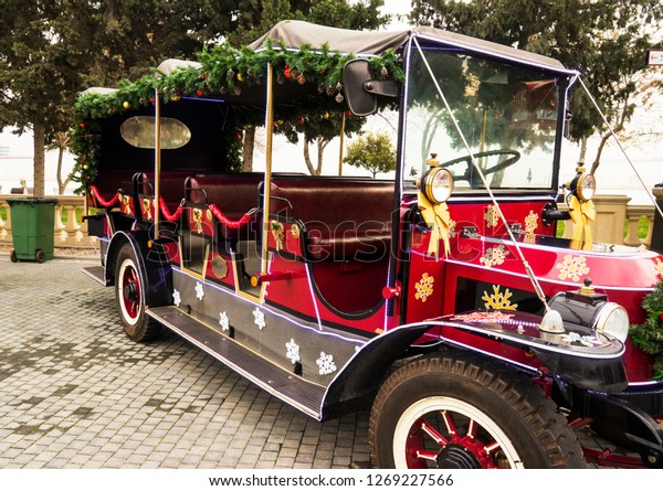 old, red walking car, bus decorated with Christmas\
toys is in the Park