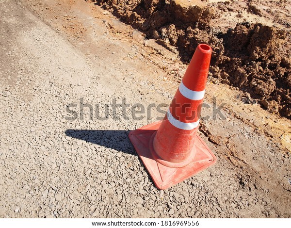 Old red and white traffic cones on the road.\
Sunny outdoors with shadow on the road construction site. Focus\
close and choose the\
subject.