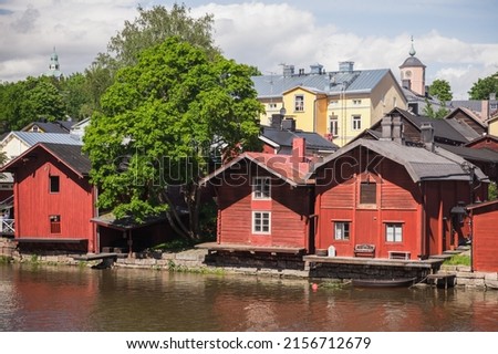 Old red wooden houses and barns stand along the river coast in old town of Porvoo, Finland