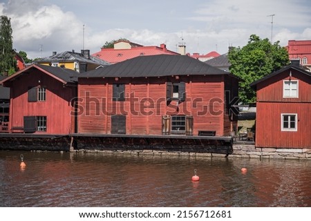 Old red wooden houses and barns stand along the river, coastal view of historical part of Porvoo town, Finland