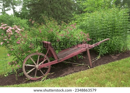 An old red wooden wagon cart in a flower garden