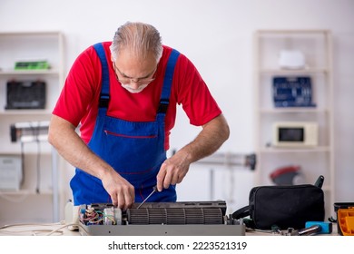 Old repairman repairing air-conditioner at workshop - Shutterstock ID 2223521319