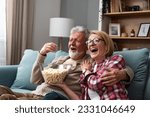 Old retired age couple watching TV at home, old mature couple cheering sport games competition together with laugh smile victory on sofa couch at living room home. Senior man and woman movie night.