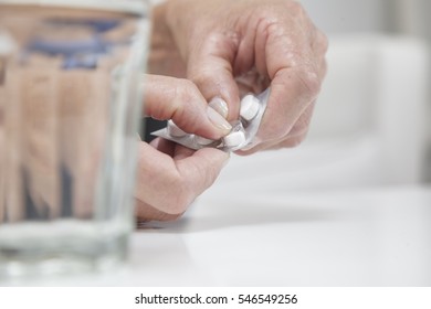 Old Retired Woman Taking Pills From A Dispenser 