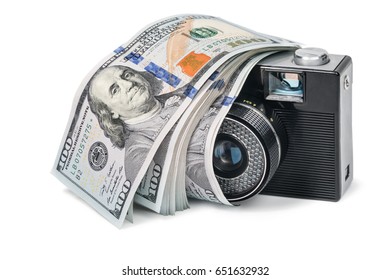 Old retro camera with a bundle of money lying on it, isolated on a white background