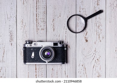 Old retro camera and magnifying glass on vintage boards in white - Powered by Shutterstock