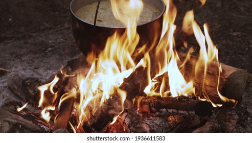 Old Retro Camp Saucepan Boiled Water For Soup Preparation On A Fire In Forest. Flame Fire Bonfire At Summer Evening.