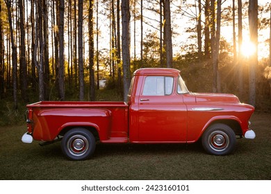 An old retro classic vintage red American pickup truck parked outside in the country with hazy light flare at sunset. - Powered by Shutterstock