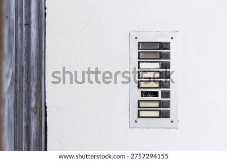 Old retro intercom panel on wall. Worn apartment entry system with missing button cover and visible wires. Vintage building communication device with aged surface and weathered detail.