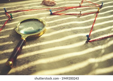 Old Retro Map Is Pressed With Magnifying Glass, Route Marked On Map With Red Thread And Buttons.Sunlight Shines Through The Blinds