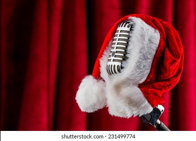 an old retro microphone with santa hat against a red velvet background. - Powered by Shutterstock