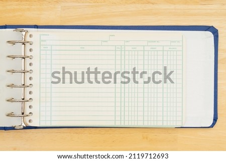 Old retro paper ledger on a wood desk to hand write debits, credits and balance
