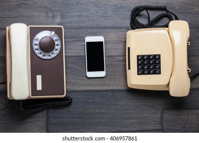 Old Retro Phone And New Cell Phone On Wooden Board, Top View