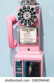 old retro pink wall phone on blue background