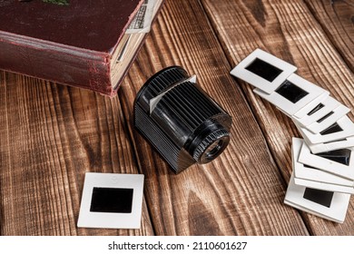 Old Retro Slide Projector, Black And White Slides And Vintage Photo Album On Brown Rustic Wood Boards