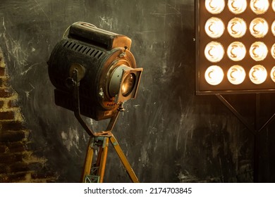 Old Retro Video Spotlight On A Stand In The Studio For Filming Movies And Photos, A Light Panel. Grunge Vintage Loft Style In Warm Colors. Close-up View.