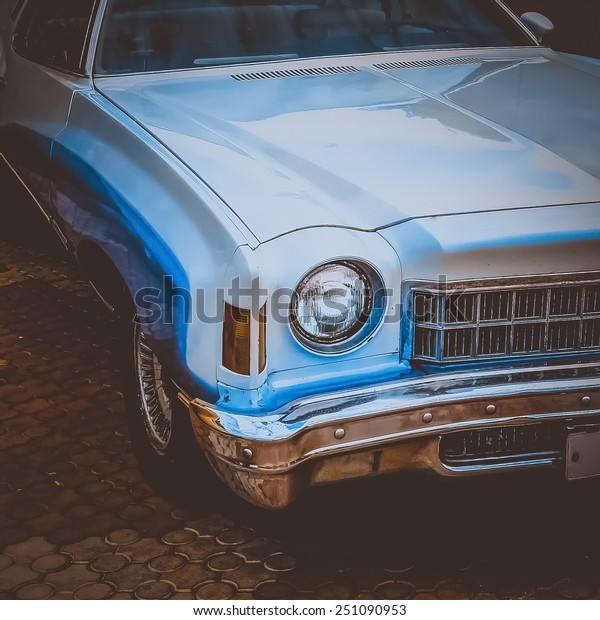 Old retro or vintage car or automobile front side\
with front light or headlight. Processed by vintage or retro effect\
filter