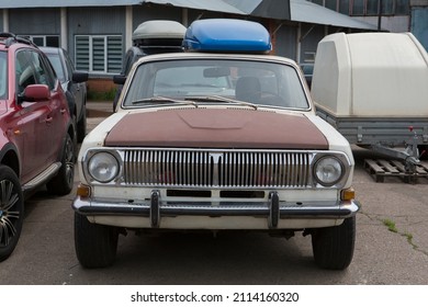 Old Retro White Soviet Car With A Rusty Bonnet Parked On A Parking Lot. Close Up Front View