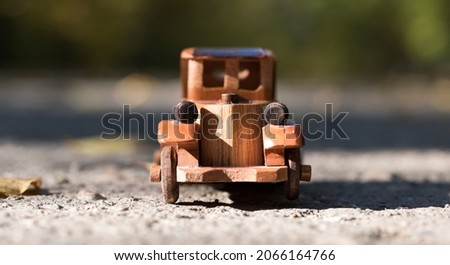 old retro wooden toy car on the road in autumn forest