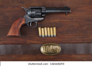 Old revolver with cartridges and U.S. Army soldier's belt with a buckle on wooden table