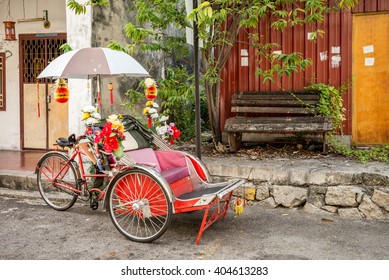 An old rickety trishaw cab parked on the sidewalk of a dilapidated building in Penang, Malaysia. - Powered by Shutterstock