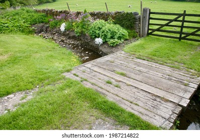 An Old Rickety Wooden Bridge Over The Stream