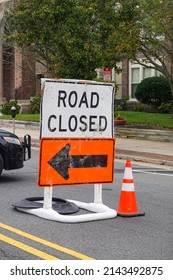 Old Road Closed Sign On Top Of An Orange Detour Sign With A Black Arrow